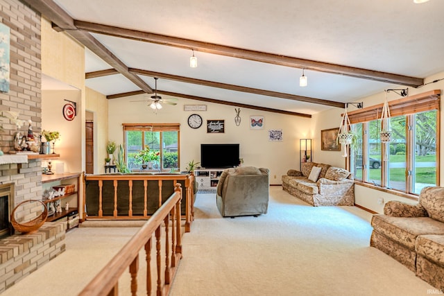 carpeted living room featuring ceiling fan, a brick fireplace, lofted ceiling with beams, and a healthy amount of sunlight