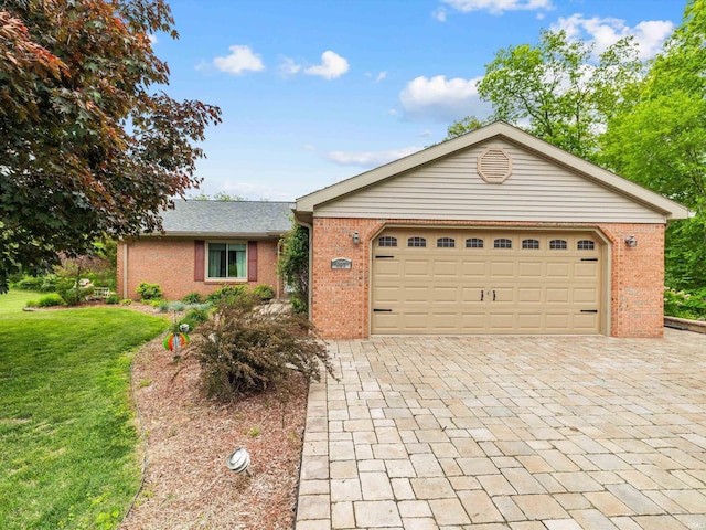ranch-style home featuring a front yard, brick siding, an attached garage, and decorative driveway