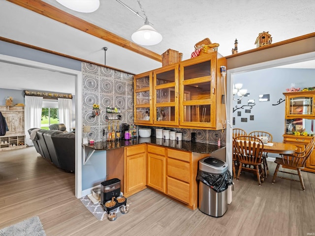 kitchen with beamed ceiling, glass insert cabinets, and light wood-style floors