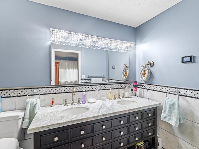 bathroom featuring a sink, double vanity, tile walls, and toilet