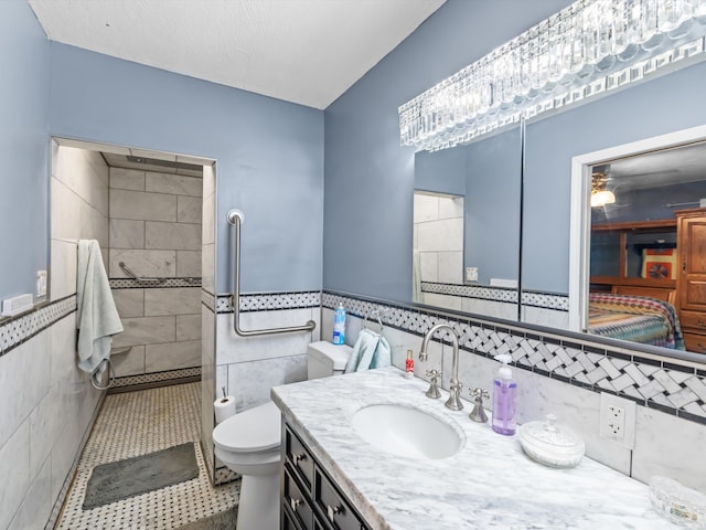 bathroom with walk in shower, tile walls, toilet, vanity, and tile patterned flooring