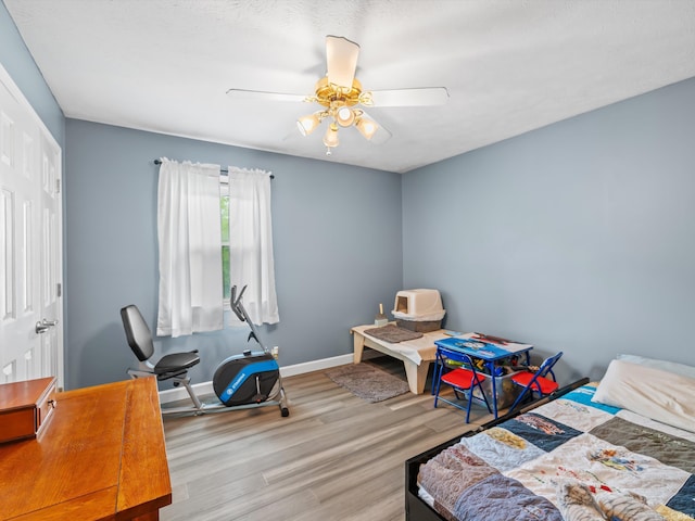 bedroom with a ceiling fan, baseboards, and wood finished floors