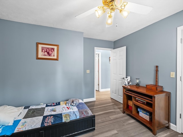 bedroom featuring wood finished floors, baseboards, and a ceiling fan