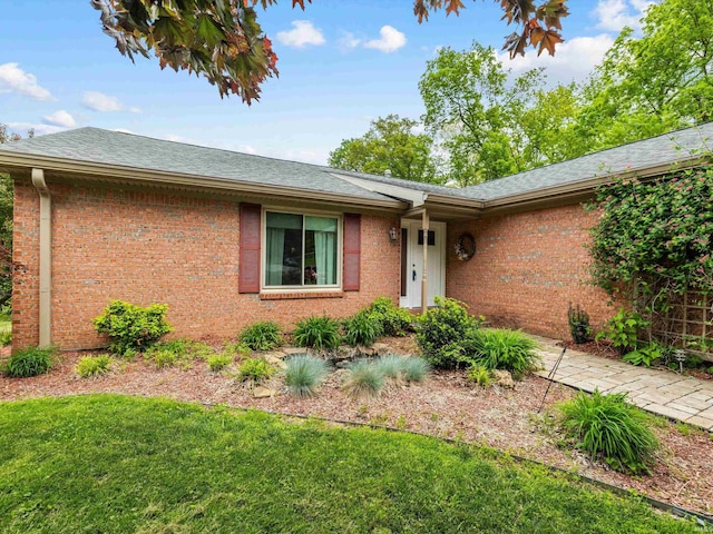 ranch-style house featuring a front yard, brick siding, and a shingled roof