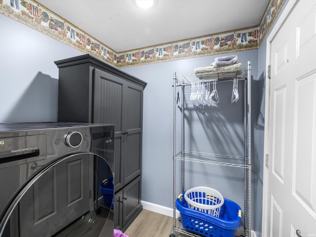 washroom featuring baseboards, washer / clothes dryer, cabinet space, and wood finished floors