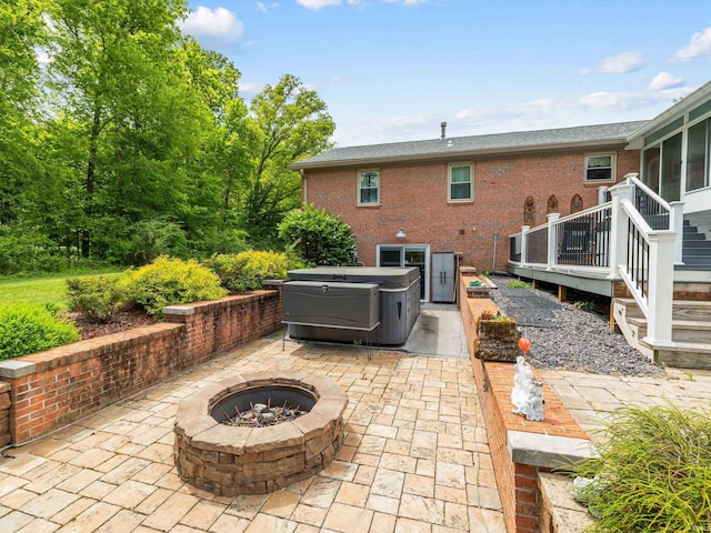view of patio featuring a hot tub, a wooden deck, and a fire pit