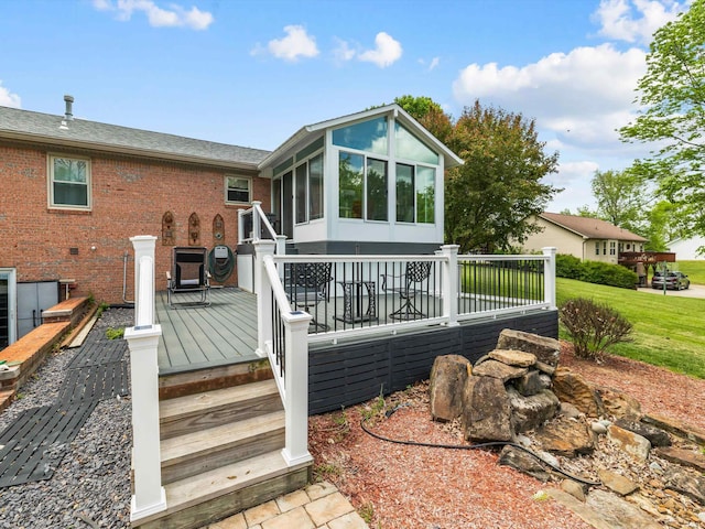 back of house featuring roof with shingles, a wooden deck, a sunroom, and brick siding