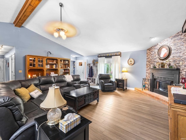 living area featuring lofted ceiling with beams, ceiling fan, a large fireplace, and wood finished floors