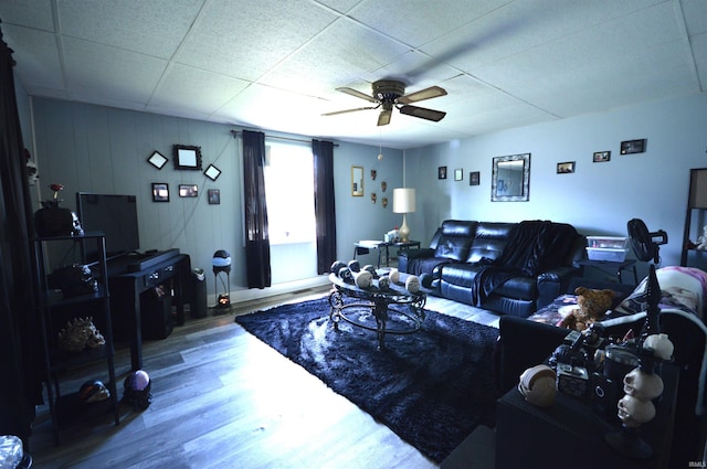 living room with a drop ceiling, wood finished floors, and ceiling fan