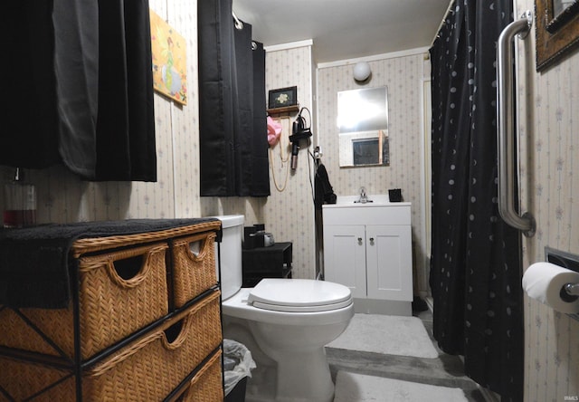 bathroom with vanity, toilet, and wallpapered walls