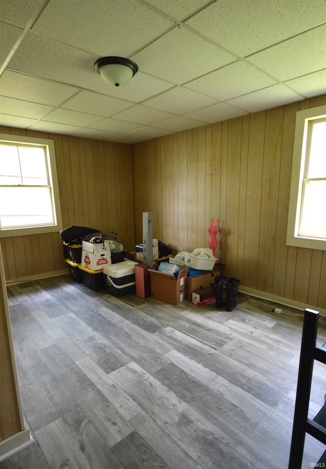 interior space featuring a drop ceiling, wood finished floors, and wooden walls