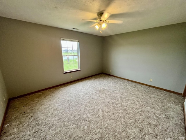 empty room with carpet floors, a ceiling fan, and visible vents