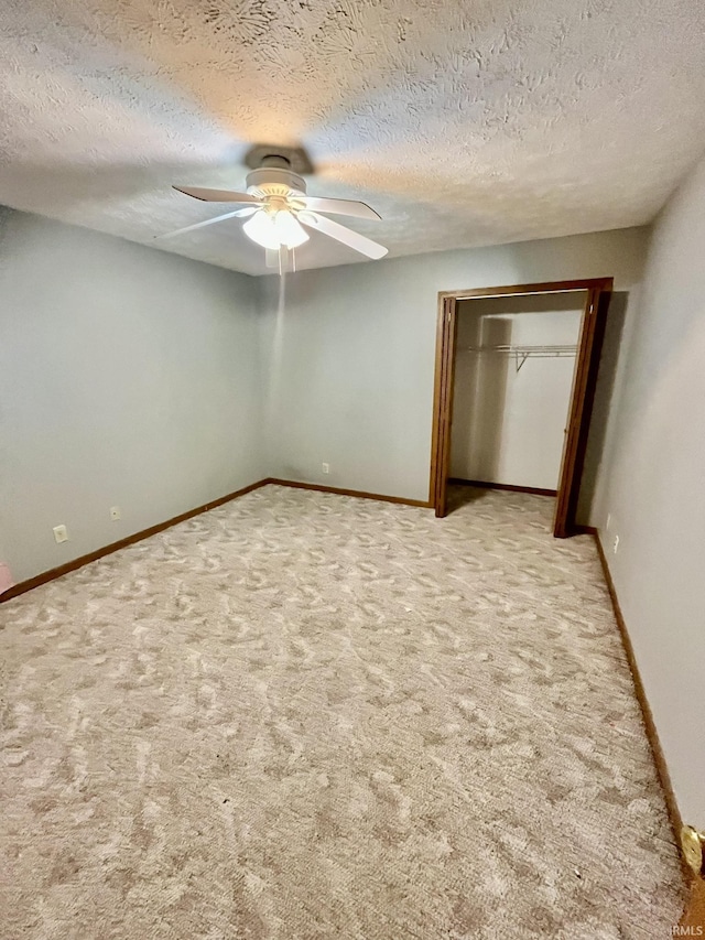 unfurnished bedroom with a textured ceiling, carpet, baseboards, and a ceiling fan