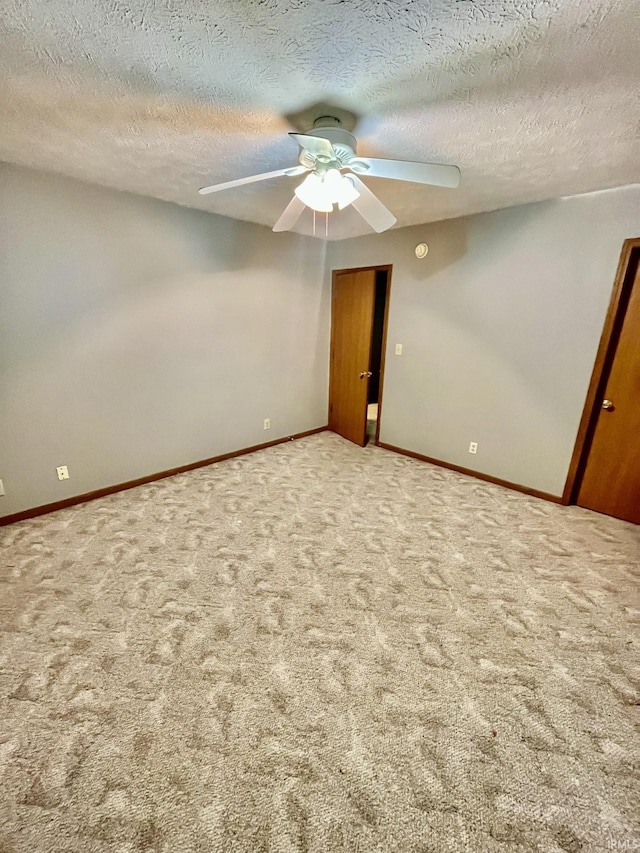 carpeted spare room with ceiling fan, a textured ceiling, and baseboards