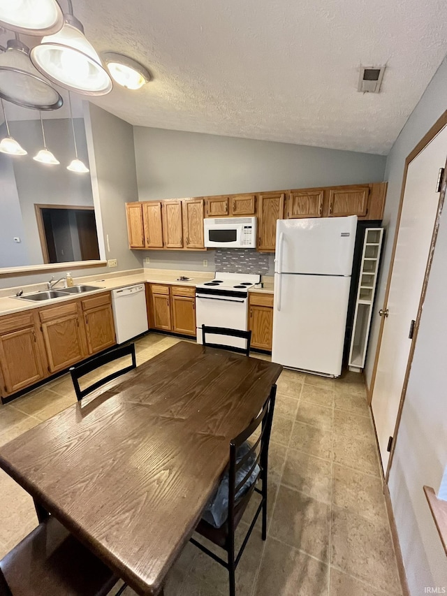 kitchen featuring lofted ceiling, a textured ceiling, white appliances, and a sink
