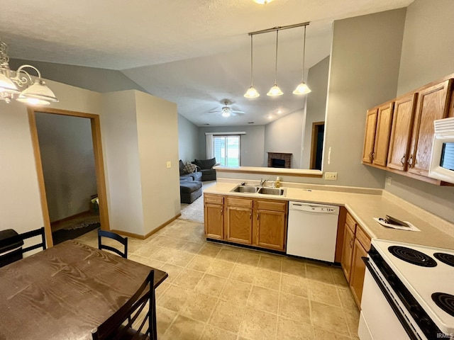 kitchen featuring a sink, vaulted ceiling, a peninsula, and white appliances