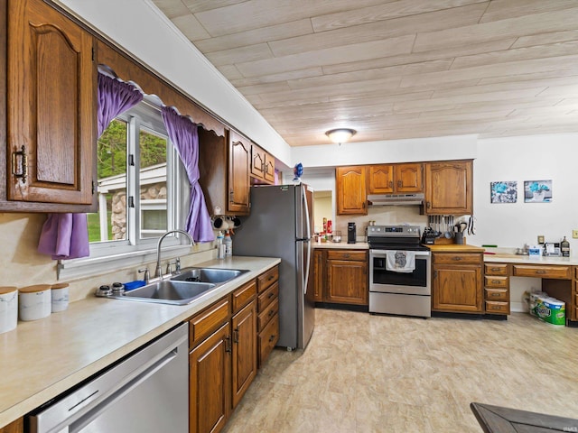 kitchen featuring a sink, brown cabinetry, stainless steel appliances, under cabinet range hood, and light countertops