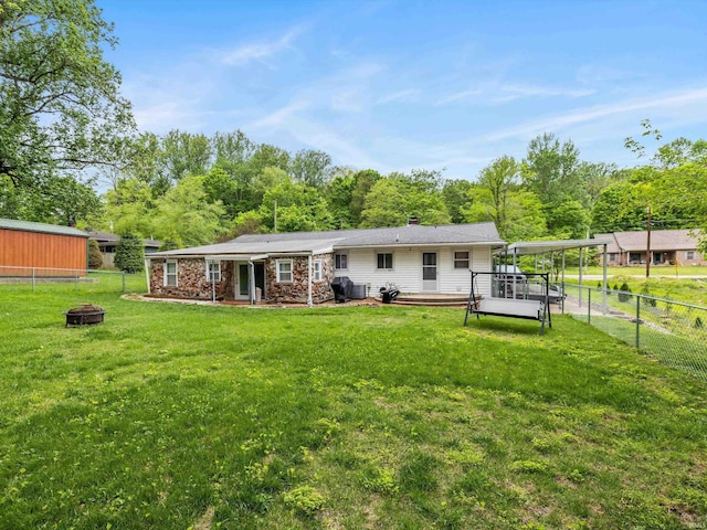 rear view of property with an outdoor fire pit, a yard, and a fenced backyard