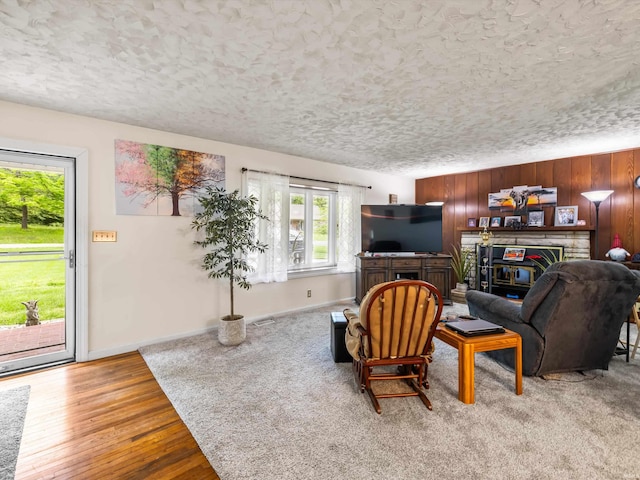 living area with a textured ceiling, visible vents, baseboards, and a glass covered fireplace