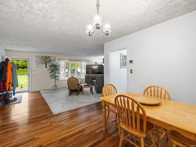 dining space with a chandelier, a textured ceiling, and wood finished floors