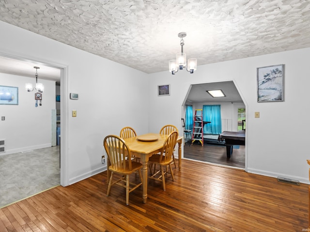 dining area featuring hardwood / wood-style flooring, a notable chandelier, and baseboards