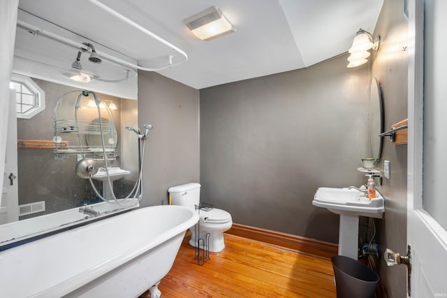 bathroom with a soaking tub, toilet, visible vents, and wood finished floors