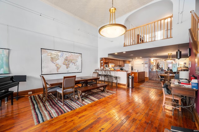 dining area with crown molding, a high ceiling, and hardwood / wood-style floors