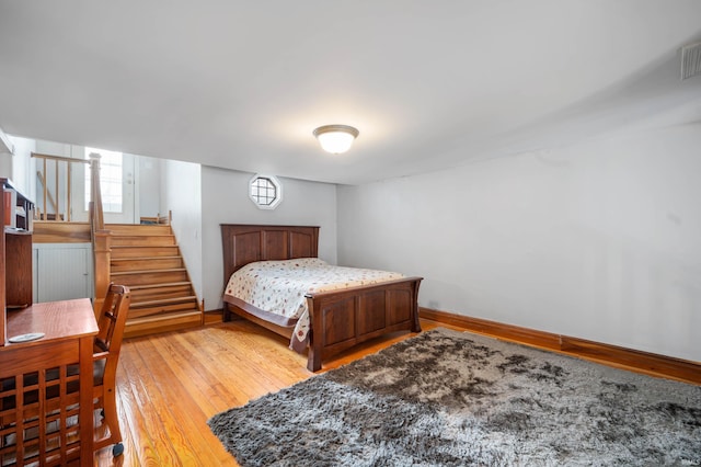 bedroom featuring baseboards, light wood finished floors, and visible vents