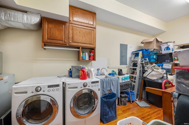 laundry room featuring electric panel, a sink, cabinet space, washer and dryer, and light wood-style flooring
