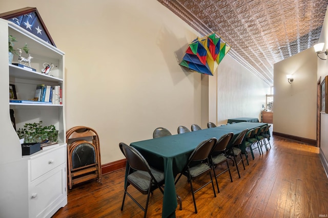 dining space featuring crown molding, wood-type flooring, baseboards, and an ornate ceiling