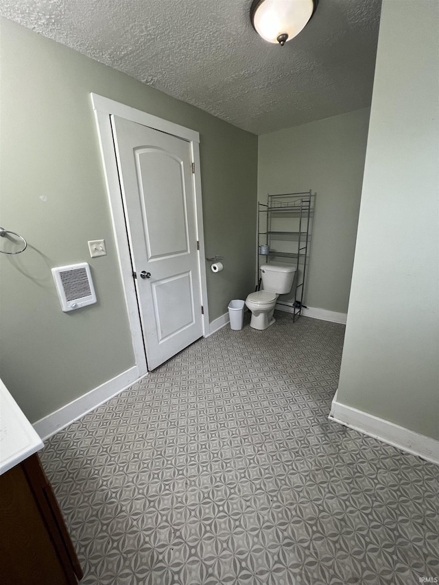 712 E Water St, Portland, IN 47371 - bathroom featuring toilet, baseboards, and a textured ceiling