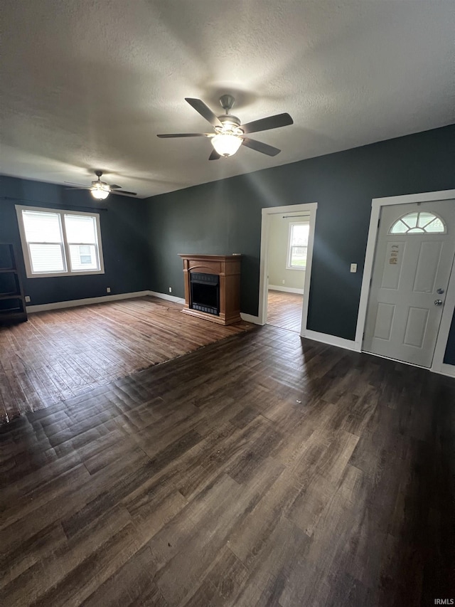 712 E Water St, Portland, IN 47371 - unfurnished living room featuring a textured ceiling, baseboards, dark wood-style flooring, ceiling fan, and a fireplace