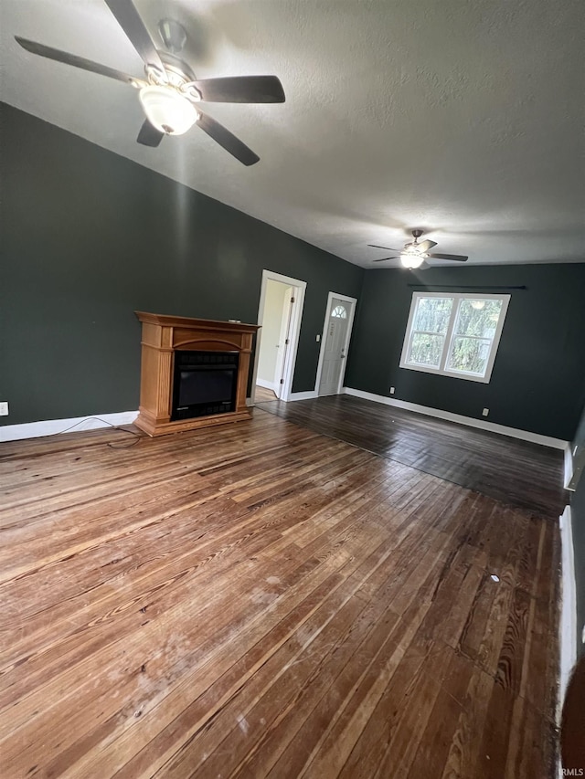 712 E Water St, Portland, IN 47371 - unfurnished living room with a textured ceiling, baseboards, ceiling fan, hardwood / wood-style flooring, and a fireplace