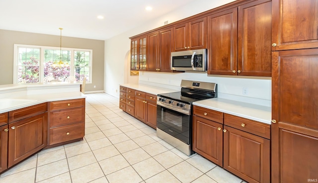 kitchen with a sink, decorative light fixtures, light countertops, light tile patterned floors, and appliances with stainless steel finishes