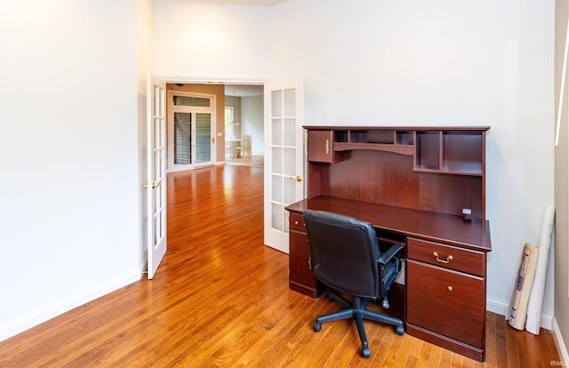 office area with french doors, light wood-style flooring, and baseboards
