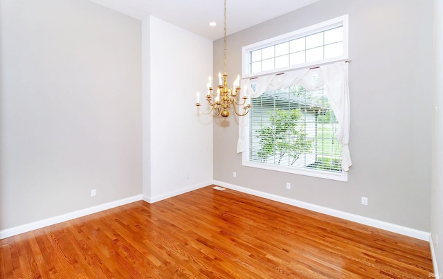 unfurnished room featuring a chandelier, light wood-style flooring, and baseboards