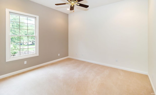 empty room featuring light colored carpet, baseboards, and ceiling fan