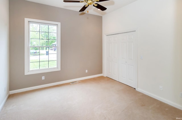 unfurnished bedroom with a closet, visible vents, baseboards, ceiling fan, and light colored carpet