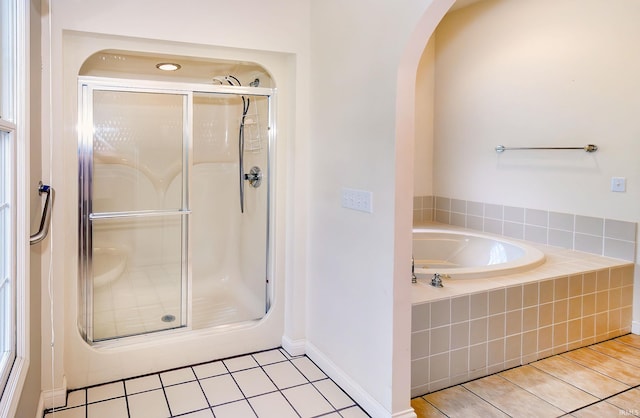 full bathroom with a stall shower, baseboards, tile patterned floors, and a garden tub