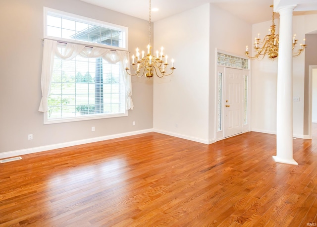 unfurnished dining area with light wood finished floors, a wealth of natural light, visible vents, and a notable chandelier