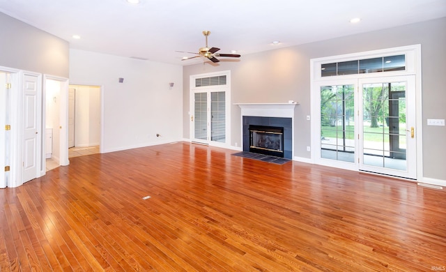 unfurnished living room featuring light wood finished floors, recessed lighting, a ceiling fan, and a tile fireplace
