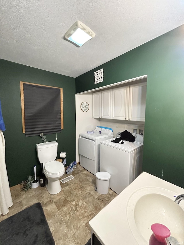 bathroom with washing machine and dryer, toilet, vanity, and a textured ceiling