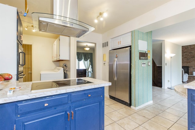 kitchen featuring freestanding refrigerator, island exhaust hood, blue cabinetry, black electric stovetop, and separate washer and dryer