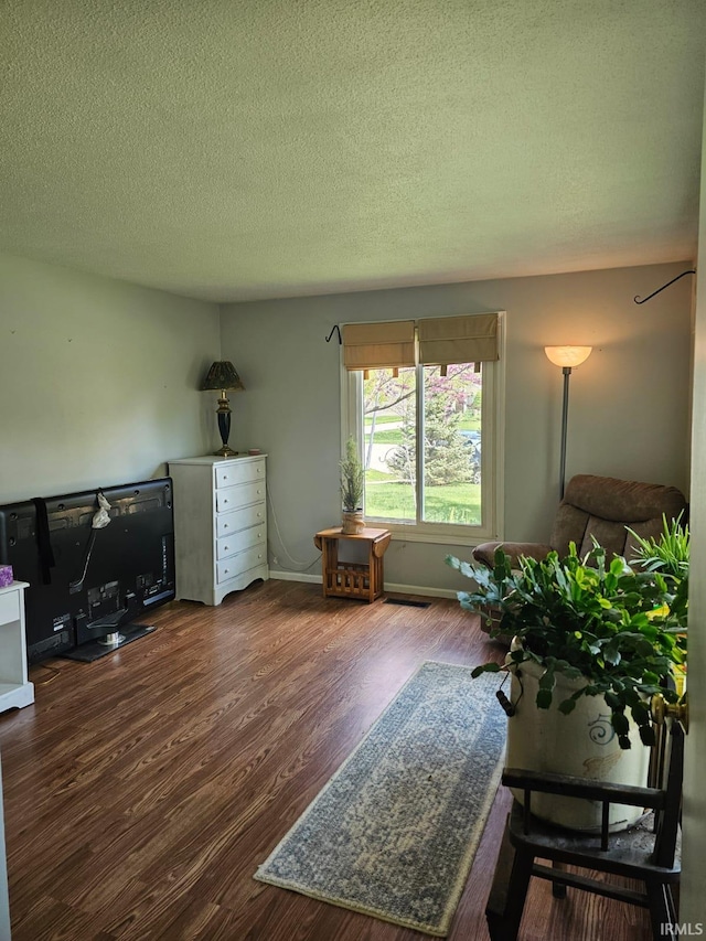 interior space with a textured ceiling, wood finished floors, and baseboards