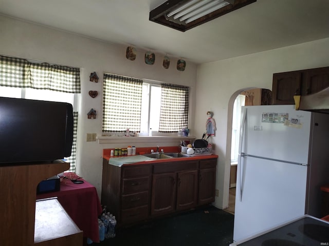 kitchen with freestanding refrigerator, a sink, and arched walkways