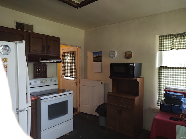 kitchen with under cabinet range hood, white appliances, and visible vents