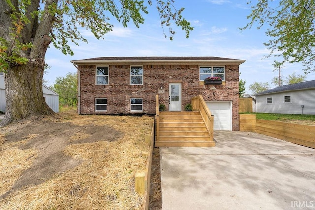 raised ranch featuring driveway, brick siding, and a garage