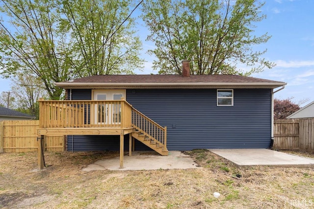 rear view of house with fence, stairs, a patio area, a wooden deck, and roof with shingles