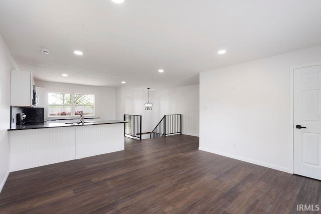 kitchen with dark countertops, dark wood finished floors, a peninsula, and recessed lighting