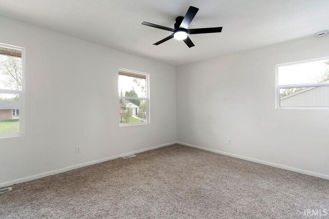 carpeted empty room featuring a wealth of natural light, baseboards, and a ceiling fan